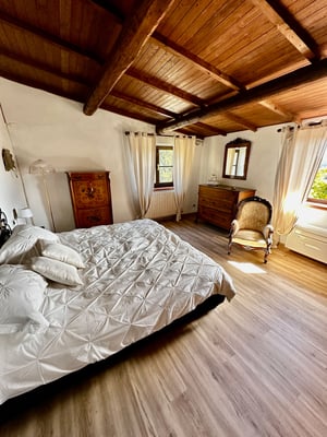 Letto matrimoniale con testiera in ferro battuto e biancheria decorata, accanto a un grande armadio in legno lucidato.