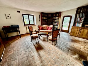 Accogliente biblioteca con pavimento in cotto, scaffali in legno e divani in stile classico.